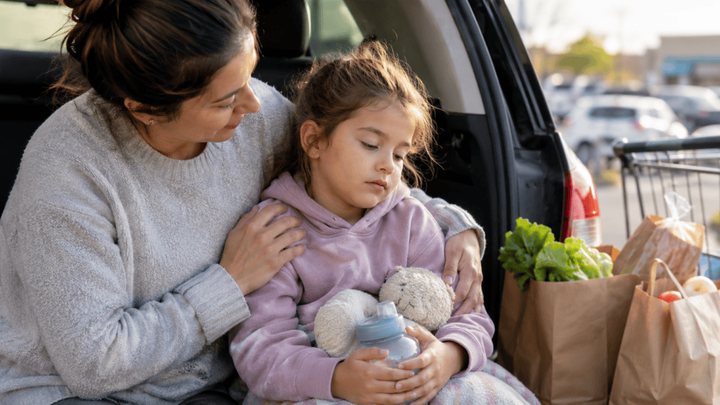 Parent comforting a tired child in the back of a car after a difficult moment at the supermarket.